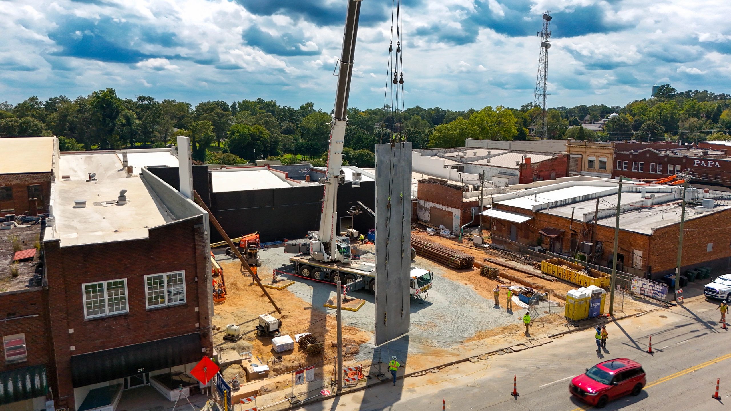 A crane raising a concrete wall panel at the Seneca Center for the Arts construction site.