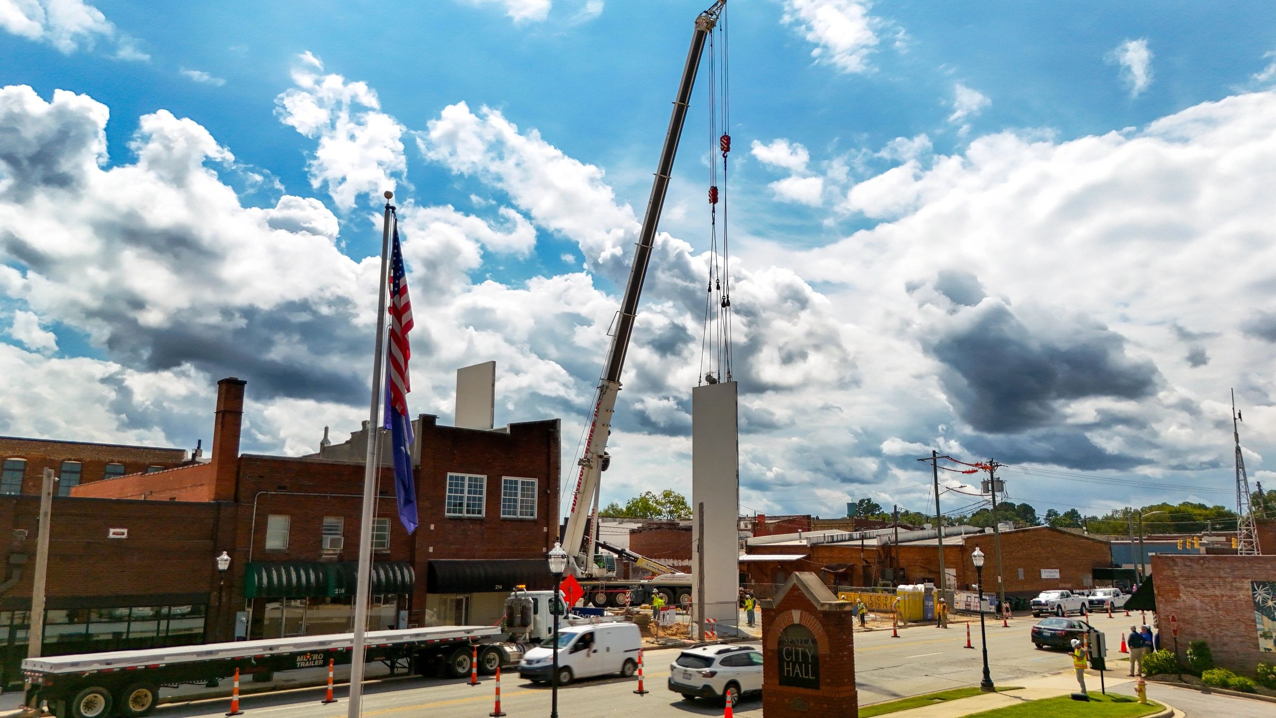 A crane lifting a concrete wall panel across from Seneca City Hall.